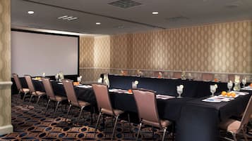 A conference room with a long table, chairs, and a projector screen.