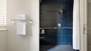 Un baño moderno con zona de ducha, un perchero y un estante con artículos de aseo.