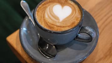Una taza de café con un diseño de corazón en la espuma, sobre un plato posado en una mesa de madera.