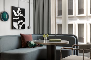 A reception area with a modern design, featuring a reflective glass partition, a patterned rug, and a decorative wall with a nature scene. at Kimpton Hotel Monaco Seattle by IHG
