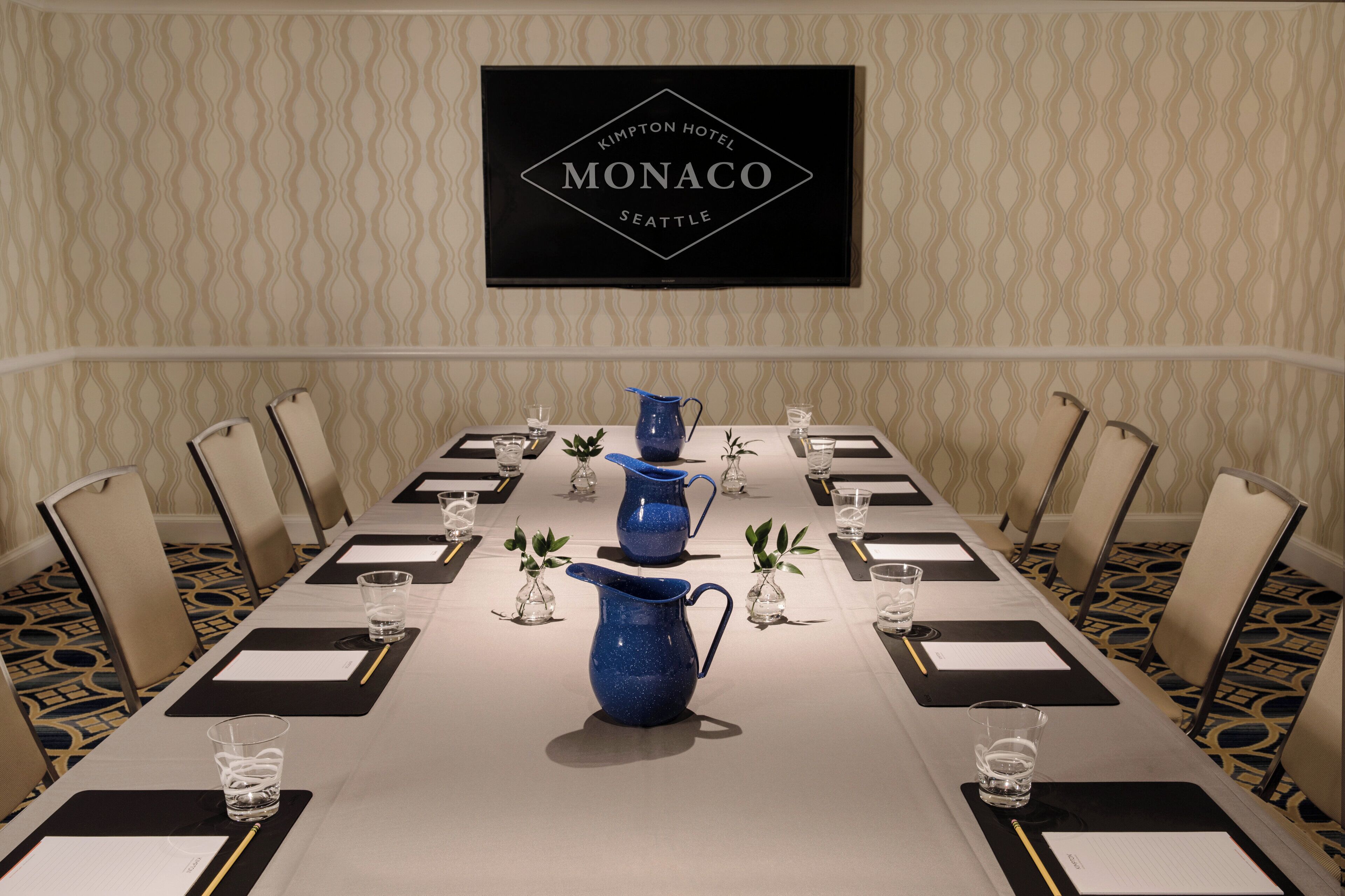 A conference room with a long table, chairs, and a sign above indicating it's the Monaco Hotel in Seattle.