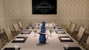 A conference room with a long table, chairs, and a sign above indicating it's the Monaco Hotel in Seattle.