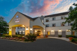 Un hotel con un llamativo letrero de 'Hyatt House', un acceso ajardinado y una fachada de edificio moderna.