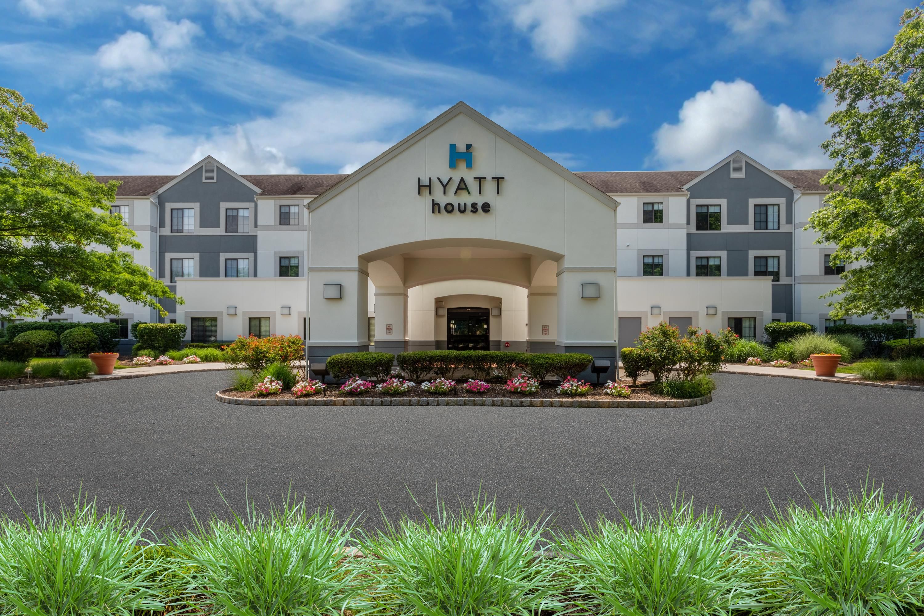 A modern hotel building with a prominent 'Hyatt House' sign, featuring a symmetrical facade with multiple windows and a central entrance.