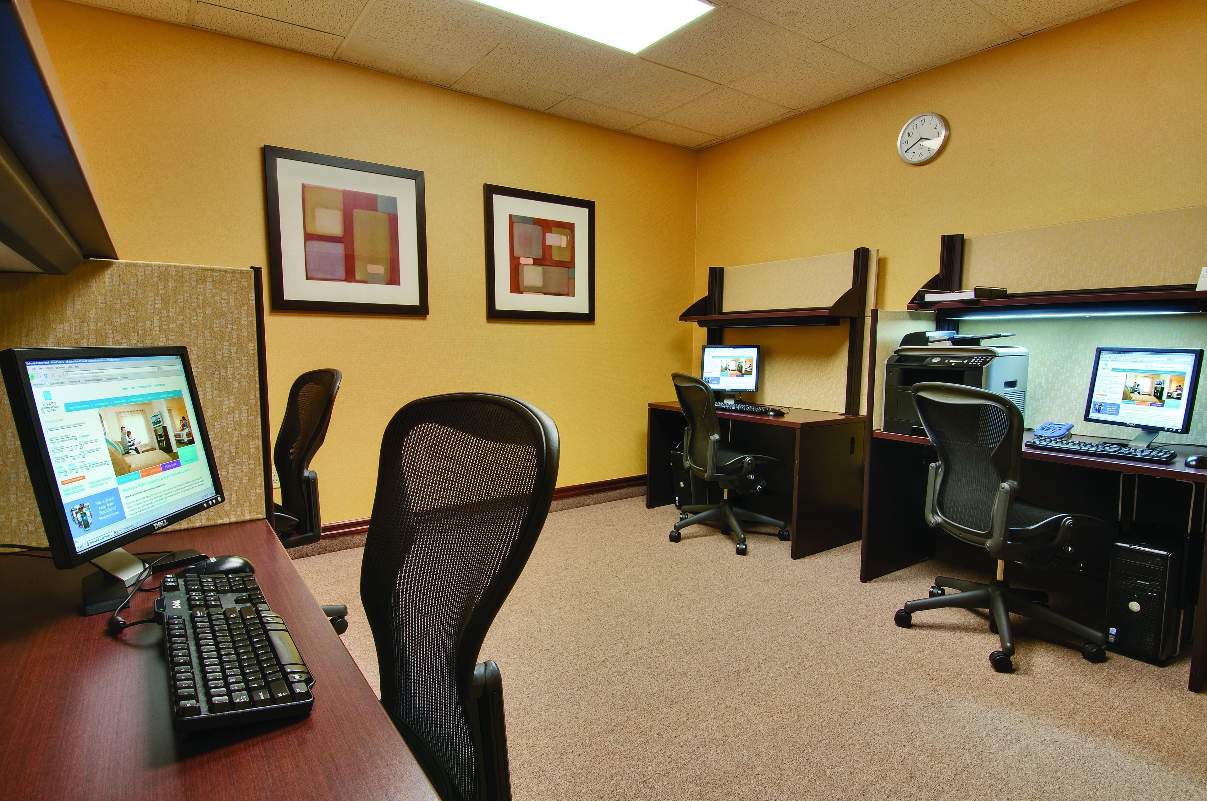 A hotel office with multiple workstations, computers, and framed artwork on the walls.
