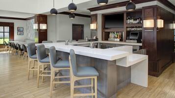 A bar area with a long counter, bar stools, and a selection of bottles.