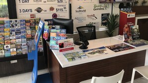 Un mostrador de venta de boletos con varios boletos para Disney y Universal Orlando Resort a la vista, una computadora y una pantalla de televisión que muestra una escena de Disney.