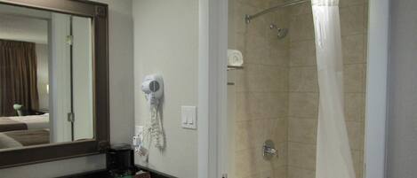A bathroom with a sink, mirror, hairdryer, and shower curtain.