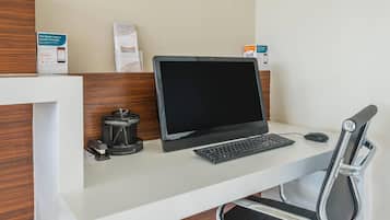 A hotel workspace with a laptop, keyboard, mouse, and a coffee machine.