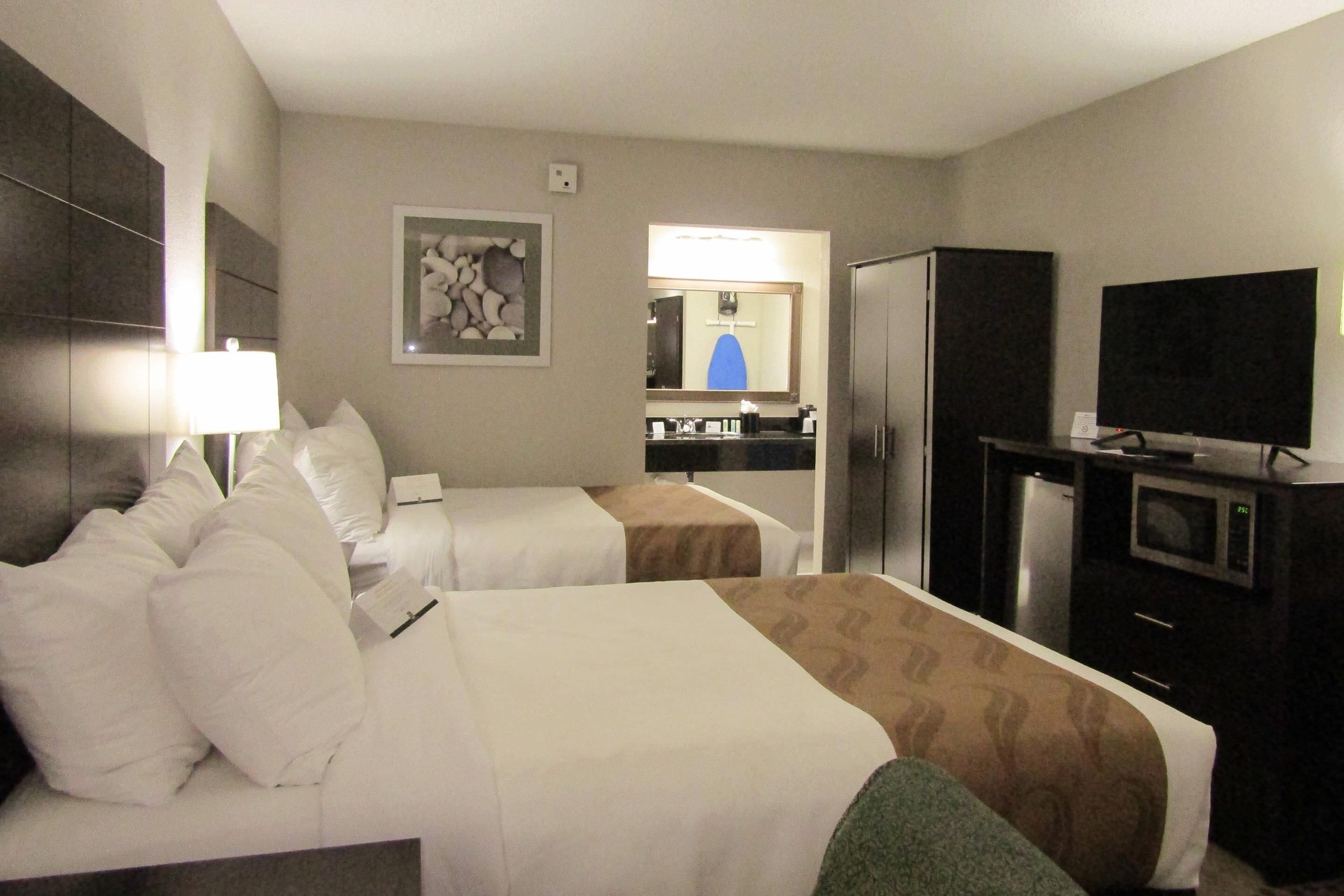 Habitación de hotel con dos camas, televisión, refrigerador y microondas.