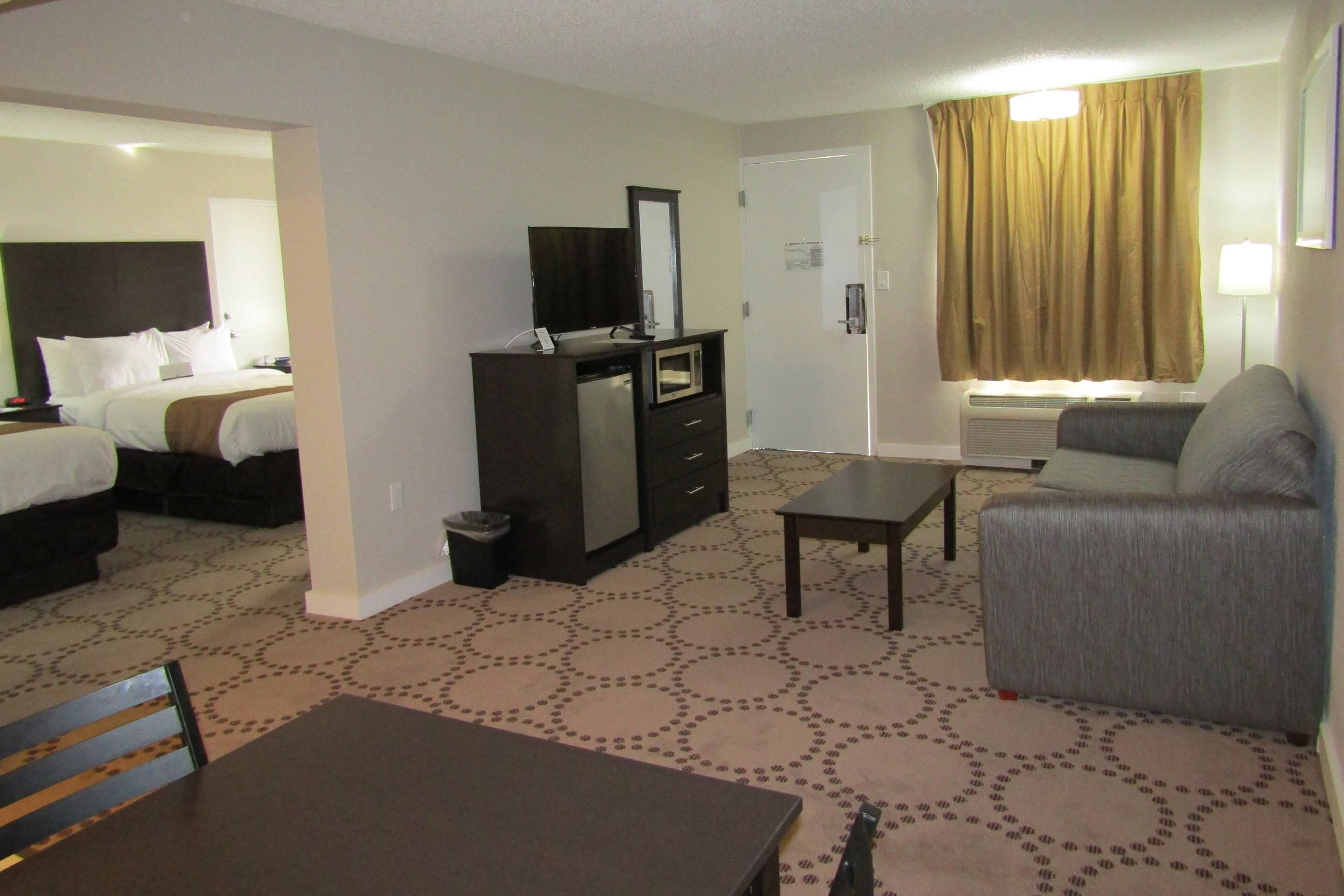 Une chambre d’hôtel comprenant un lit, un bureau, une chaise, une commode et un téléviseur.