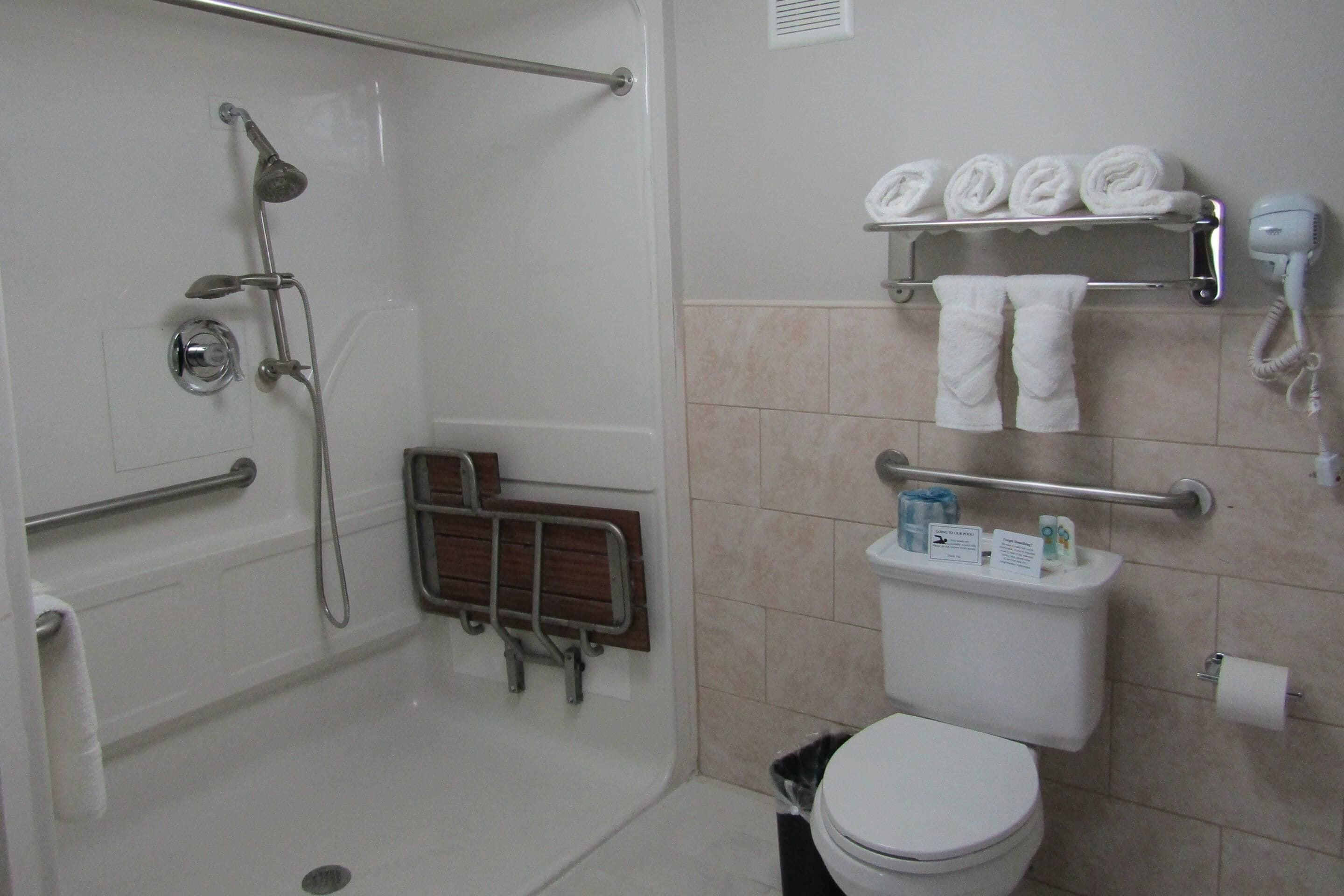 A bathroom with a shower, toilet, and hand dryer.