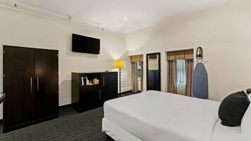 Hotelkamer met een groot bed, een kledingkast, een bureau met lamp, een televisie en een spiegel.