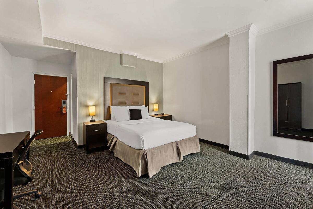 A hotel room with a bed, bedside tables, a desk, and a chair.
