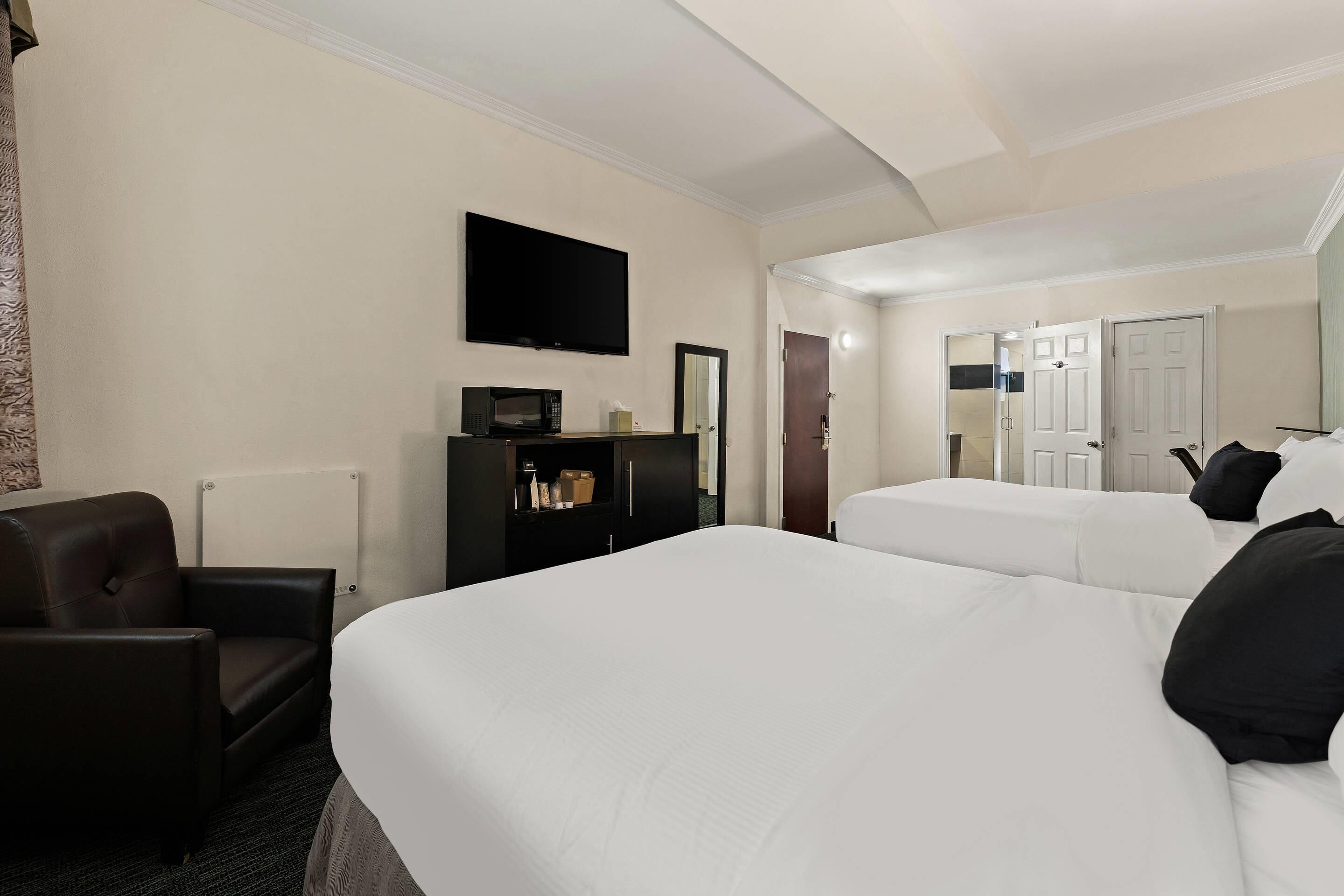 A hotel room with two beds, a desk, a chair, a TV, and a wardrobe.