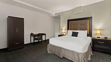 Een hotelkamer met een groot bed, een bureau, een kledingkast en twee nachtkastjes met lampen.