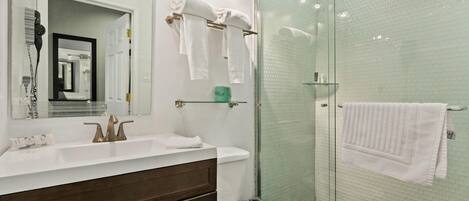 Un baño moderno con lavamanos blanco, cabina de ducha de vidrio y un inodoro.