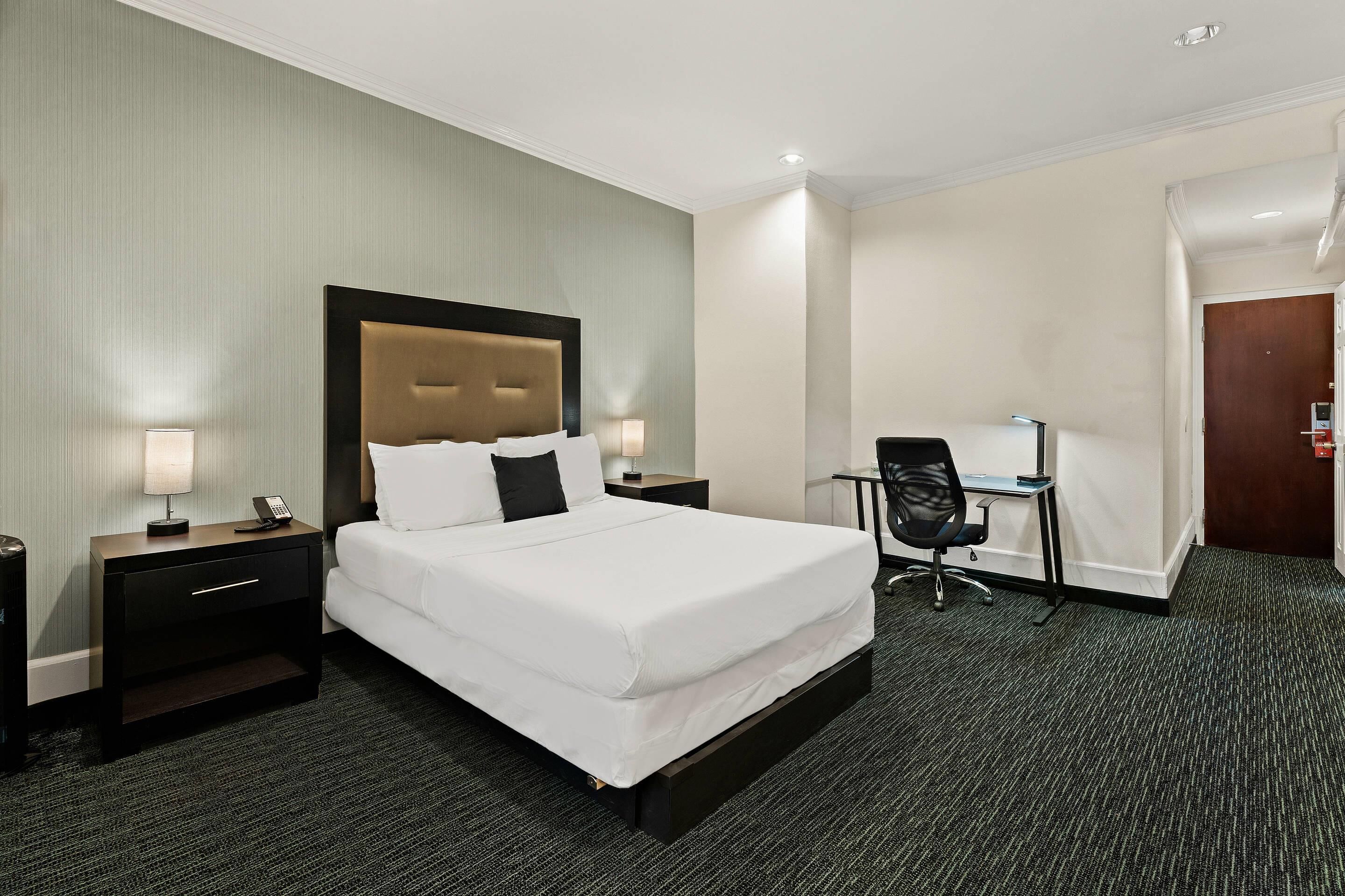 Een hotelkamer met een groot bed, een bureau en een stoel.