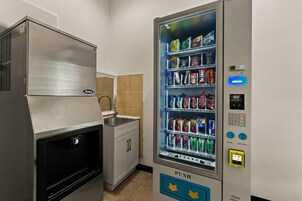 Máquina expendedora con diversas opciones de bocadillos y bebidas, un botón para la devolución de monedas y una pantalla digital.