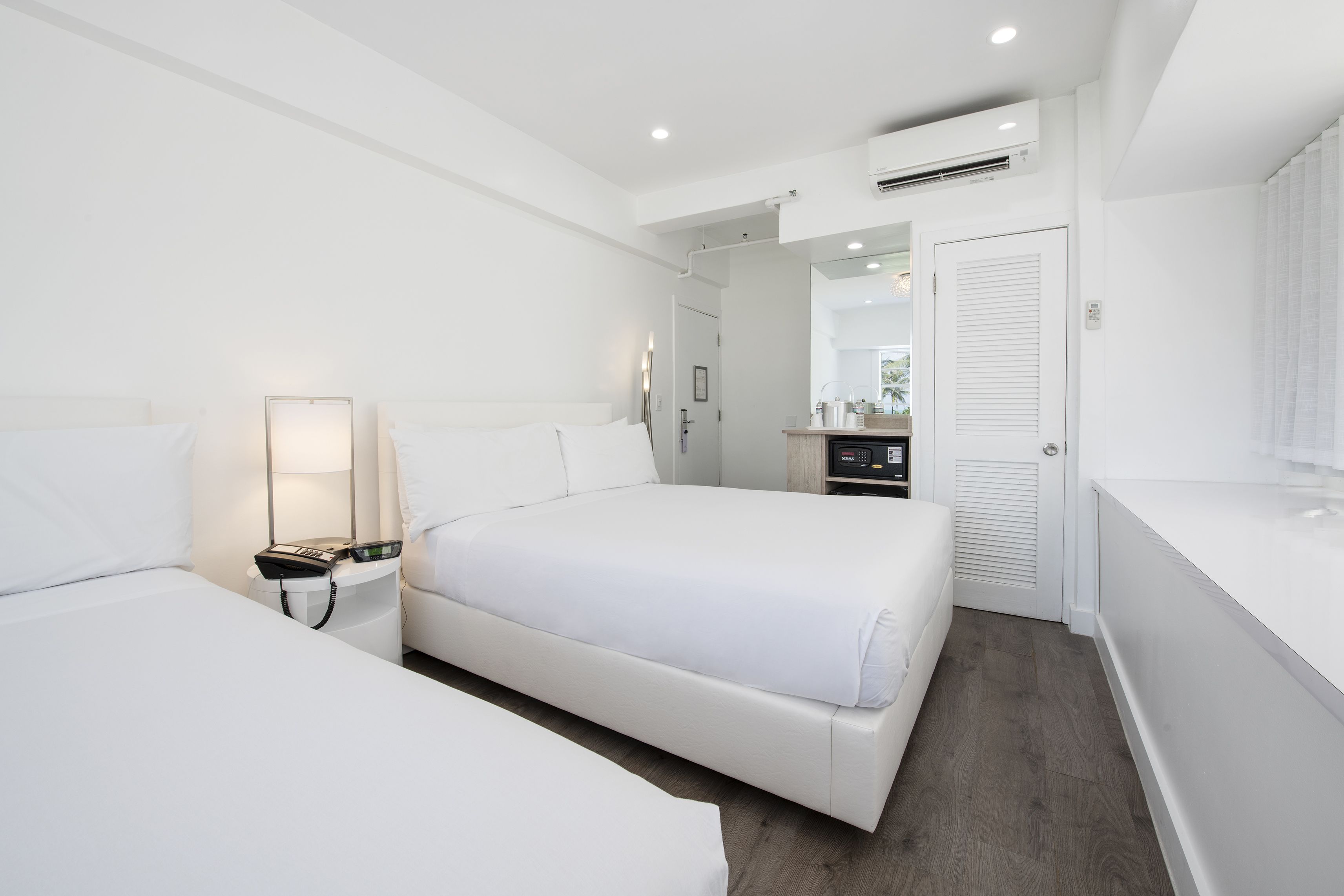 A modern hotel room with a large bed, bedside tables, a desk, and a bathroom with a shower.