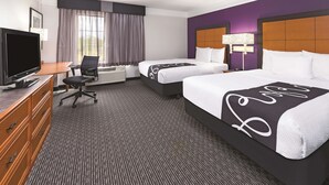 Une chambre d’hôtel avec deux lits, un bureau, une télévision et une fenêtre avec des rideaux.