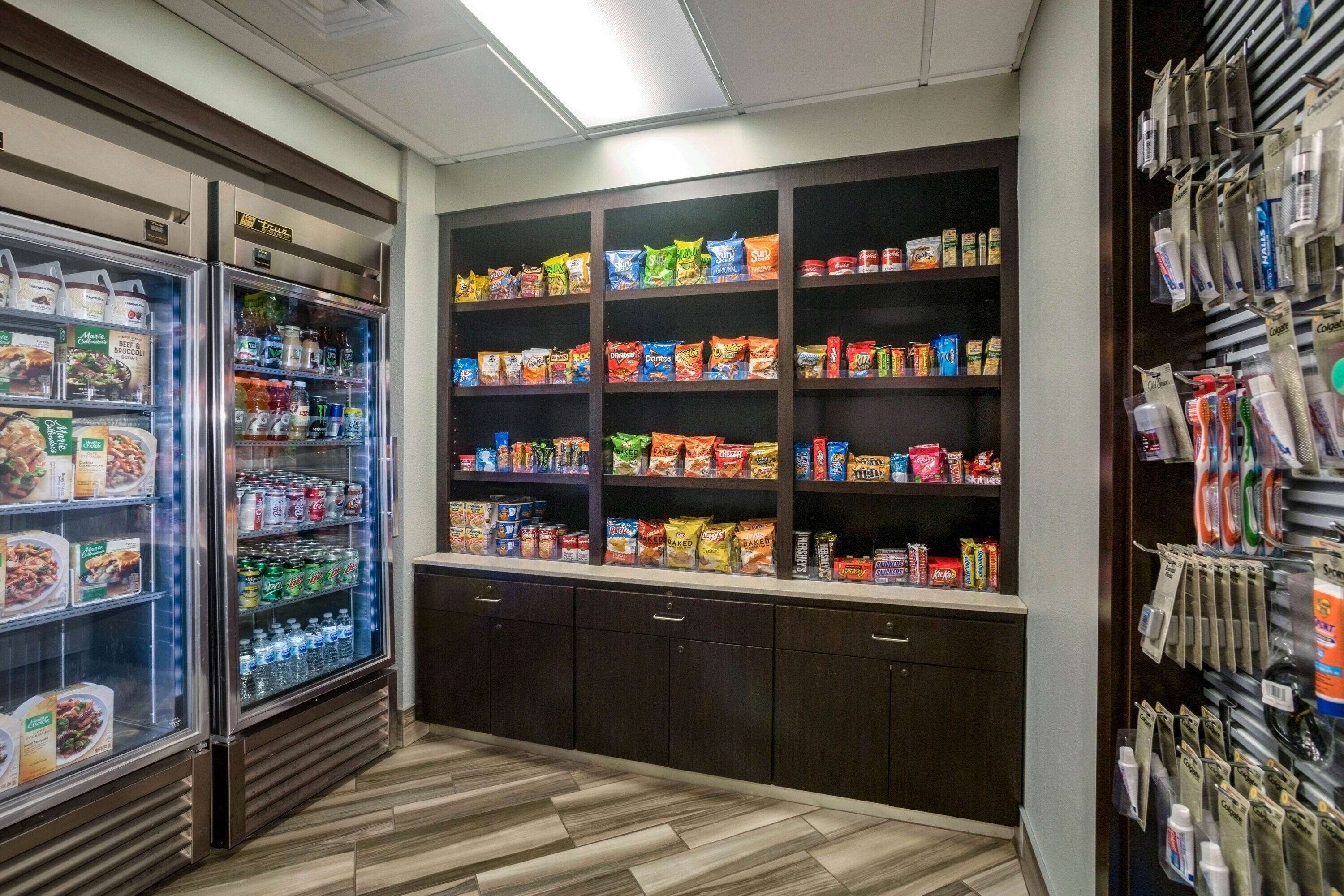 A self-service snack and beverage area with refrigerated sections and shelves stocked with various snacks and drinks.