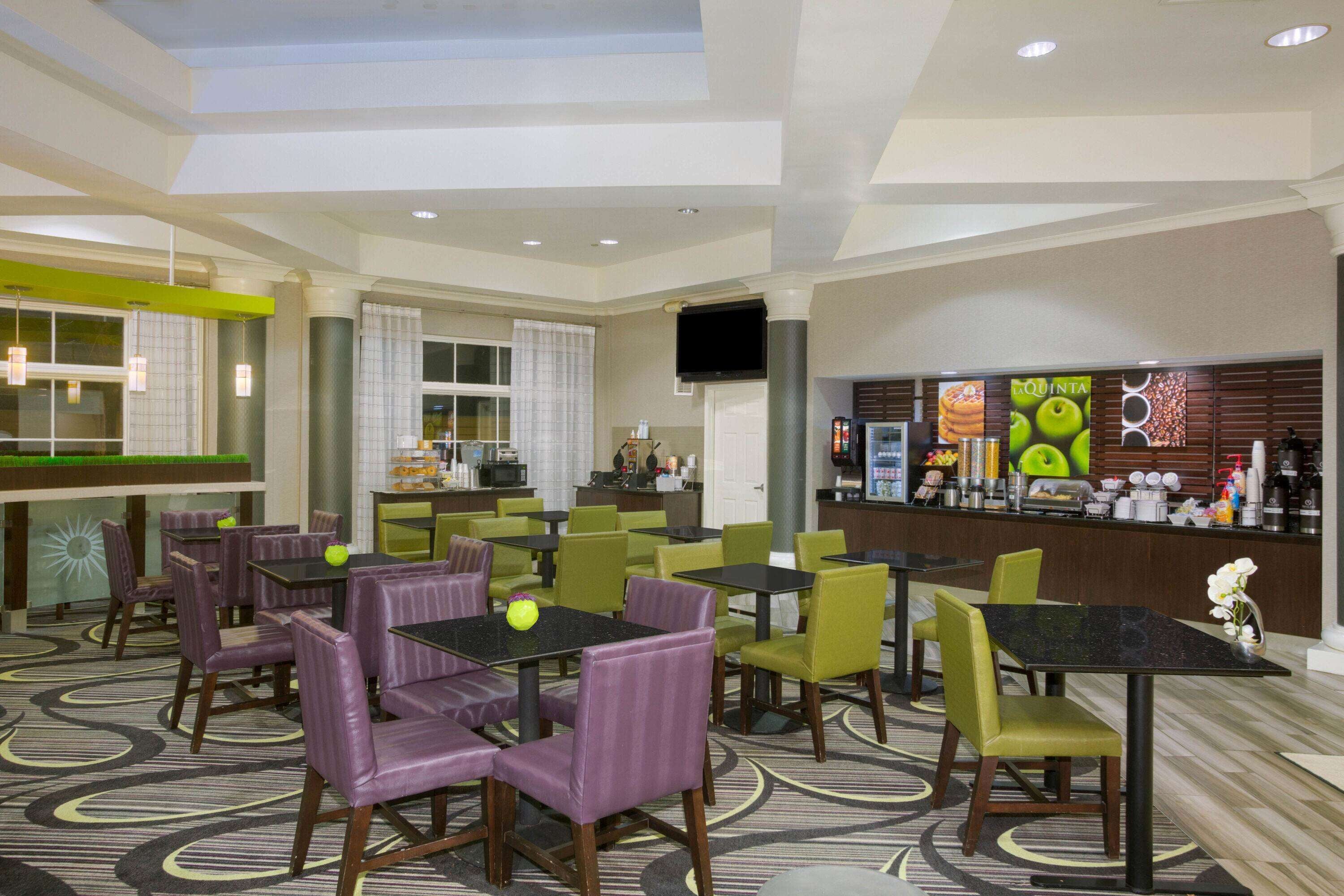 A hotel lobby with multiple seating areas, a bar, and a television screen.