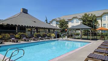 Una piscina al aire libre, sillones reclinables de piscina