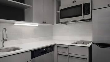 A modern kitchen with white cabinetry, a built-in microwave, a dishwasher, and a stainless steel refrigerator.