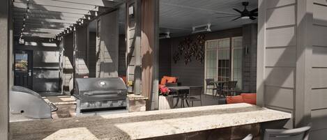 An outdoor patio with a stone countertop, grilling area, and seating.