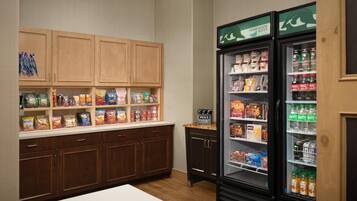 A kitchenette with wooden cabinets, a refrigerator stocked with beverages and snacks, and a microwave.
