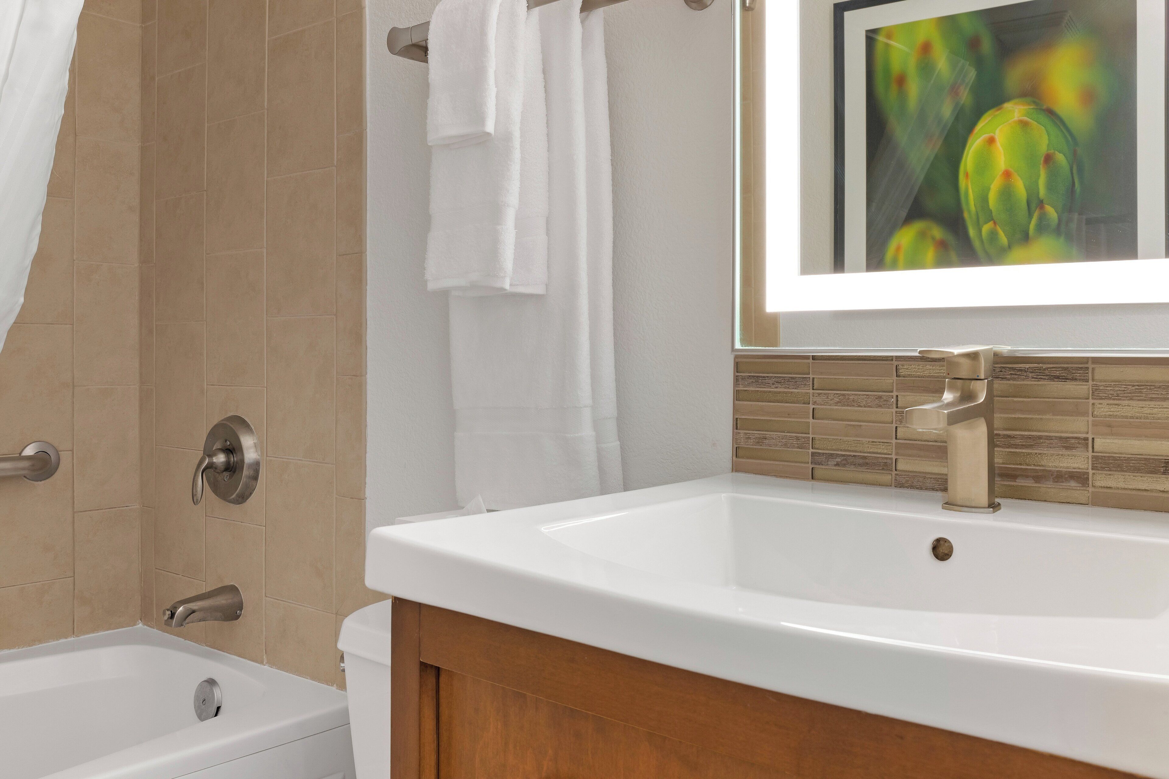 Baño con lavamanos blanco, bañera y zona de ducha.