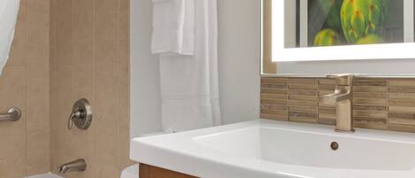 Baño con lavamanos blanco, bañera y zona de ducha.