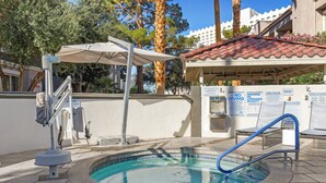 Une petite piscine extérieure agrémentée d’un élément décoratif aquatique bleu, un espace de repos couvert et un poste de surveillance pour les sauveteurs.