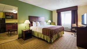 A hotel room with a bed, bedside lamps, a desk with a chair, a television, and a kitchenette. - Best Western Airport Inn & Suites Cleveland (Brook Park)