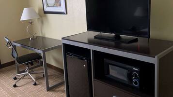 Een hotelkamer met een bureau, stoel, televisie en een minibar.