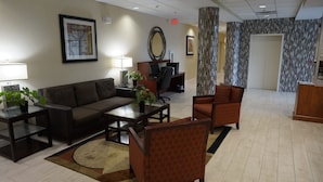 A lobby with a sofa, armchairs, a coffee table, a desk with a computer, and a reception desk. - Best Western Airport Inn & Suites Cleveland (Brook Park)