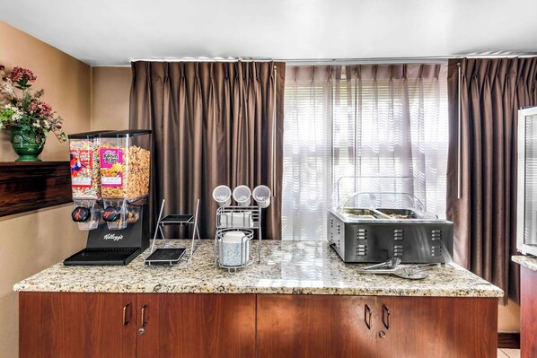 Un área de cocina con cafetera, dispensador de cereales y microondas.
