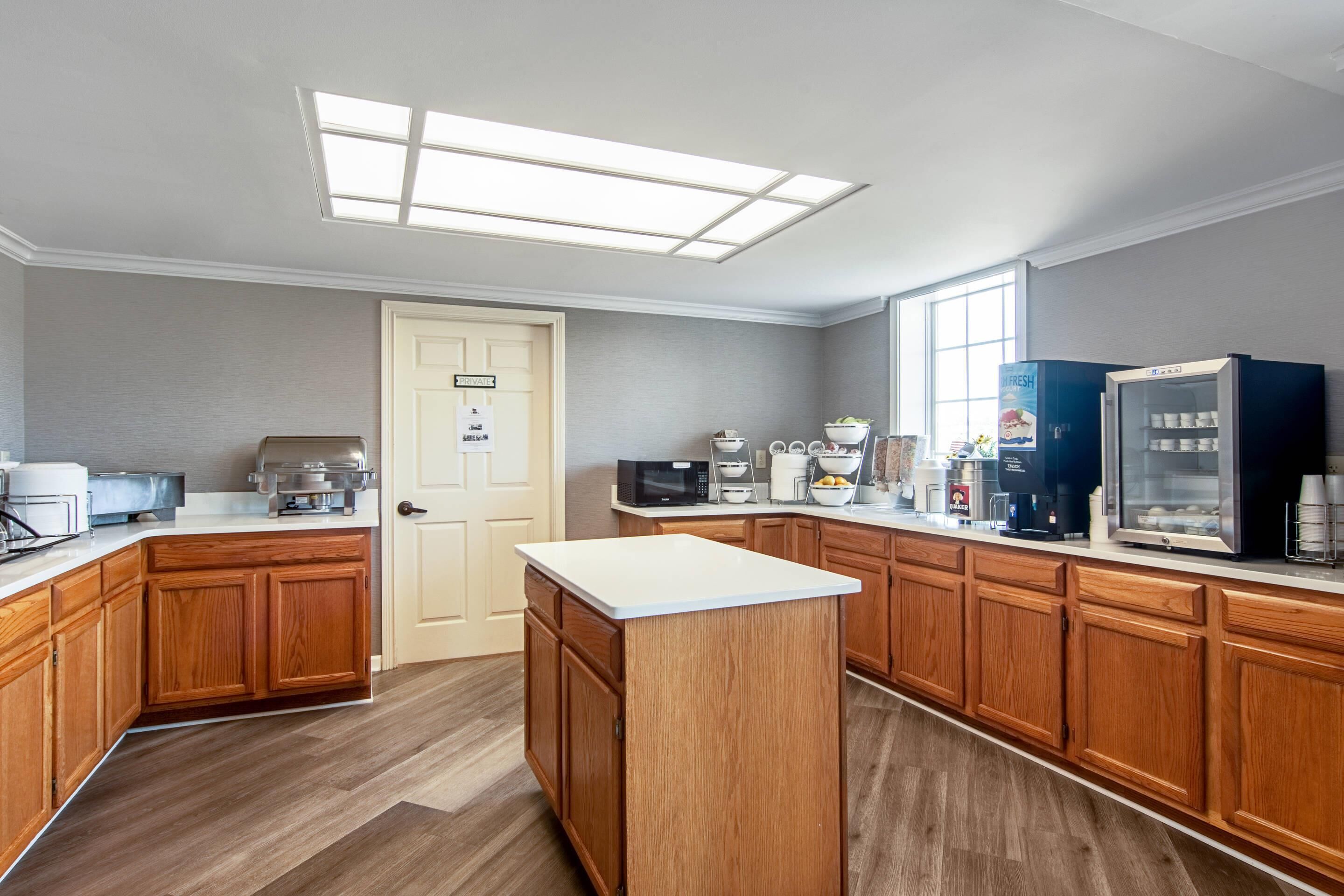 A modern kitchen with wooden cabinets, a central island, and built-in appliances.