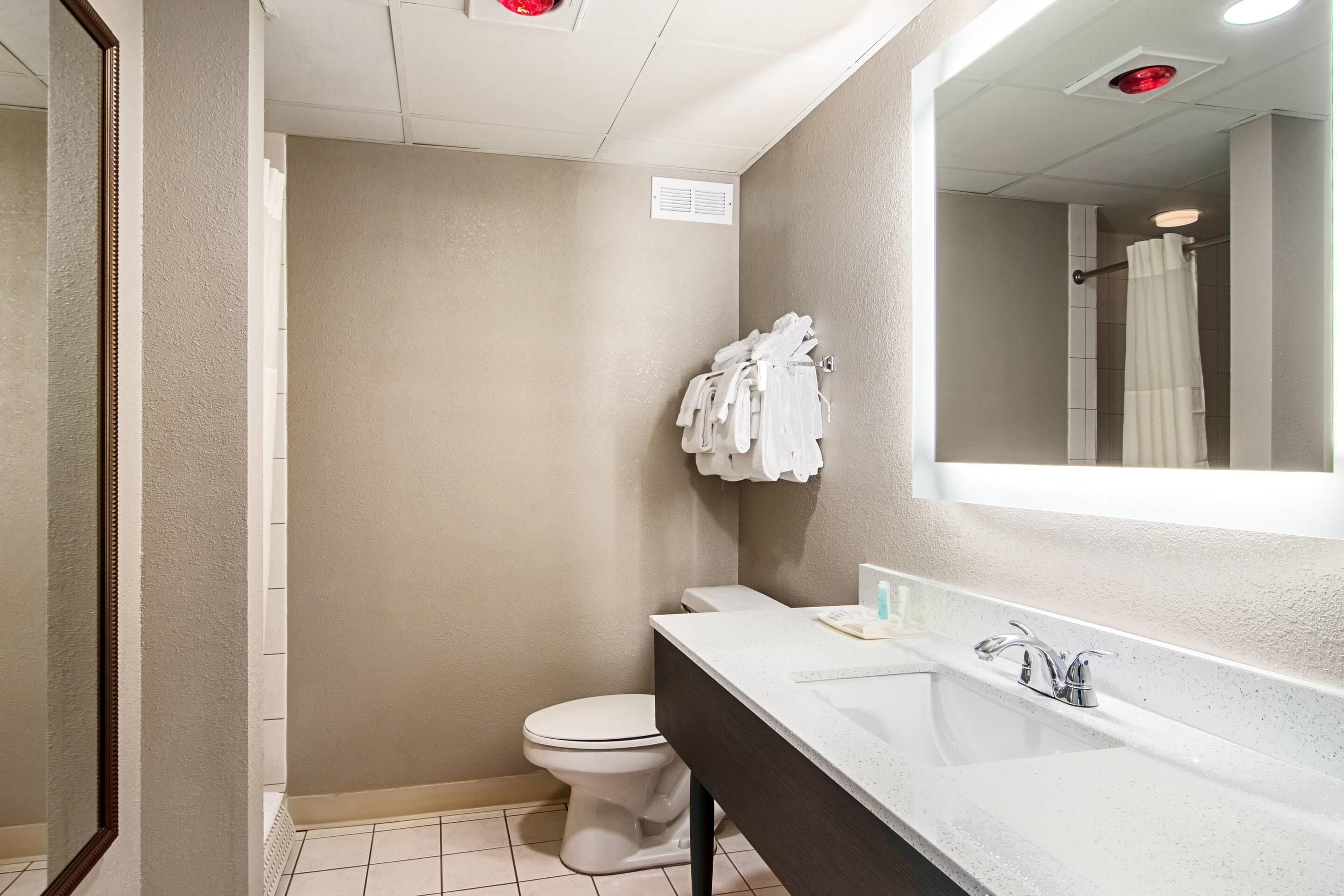 Une petite salle de bain avec des toilettes blanches, un lavabo avec un miroir et un porte-serviettes.