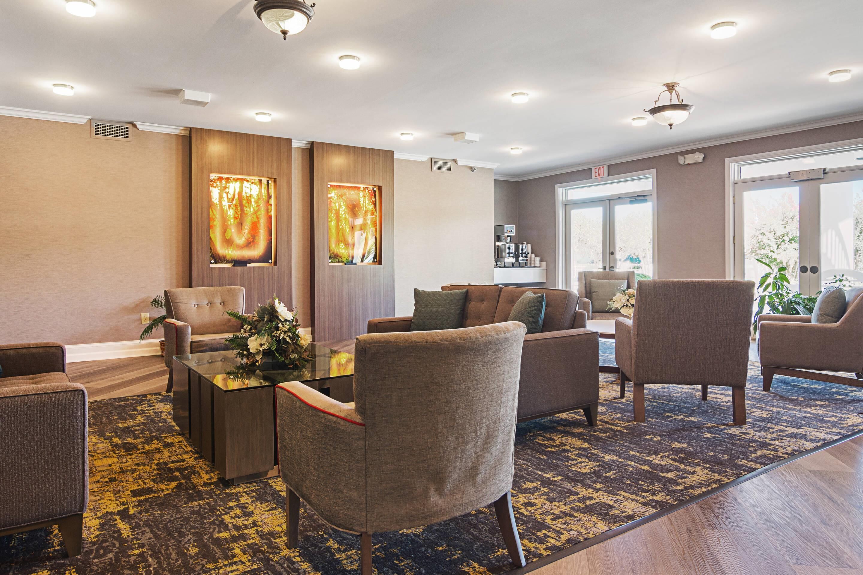 A modern lobby with a sofa, chairs, a coffee station, and artwork on the walls.