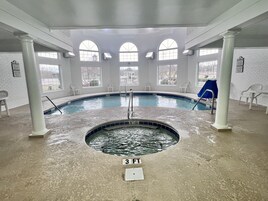 An indoor swimming pool with a 3 FT depth marker, white walls, and arched windows.