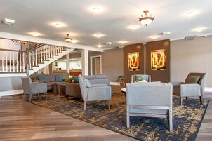 A spacious living area with a staircase, modern furniture, and decorative wall art.