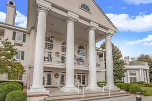 A large, two-story building with a grand entrance featuring a portico supported by columns.