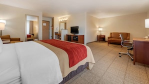 A hotel room with a large bed, a desk, a chair, a TV, and a bathroom visible through an open door. - Comfort Inn Limon (Limon)