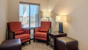 A hotel room with two armchairs, a small table, a lamp, and a view of a building through a window. - Comfort Inn Limon (Limon)
