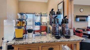 A kitchen area with a coffee machine, a blender, and a coffee press. There are multiple coffee makers and a coffee pot on the counter.