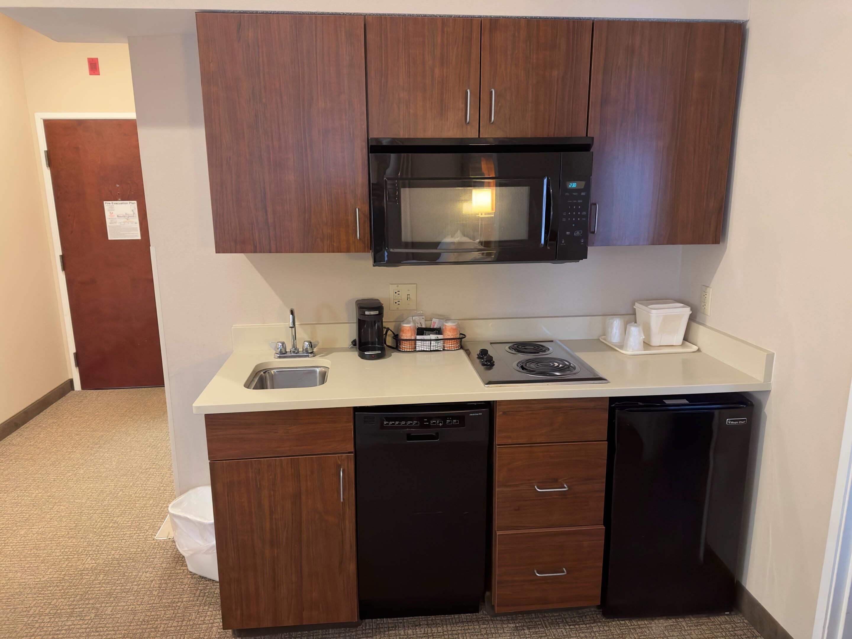 A compact kitchenette with a microwave, coffee maker, and a dishwasher.