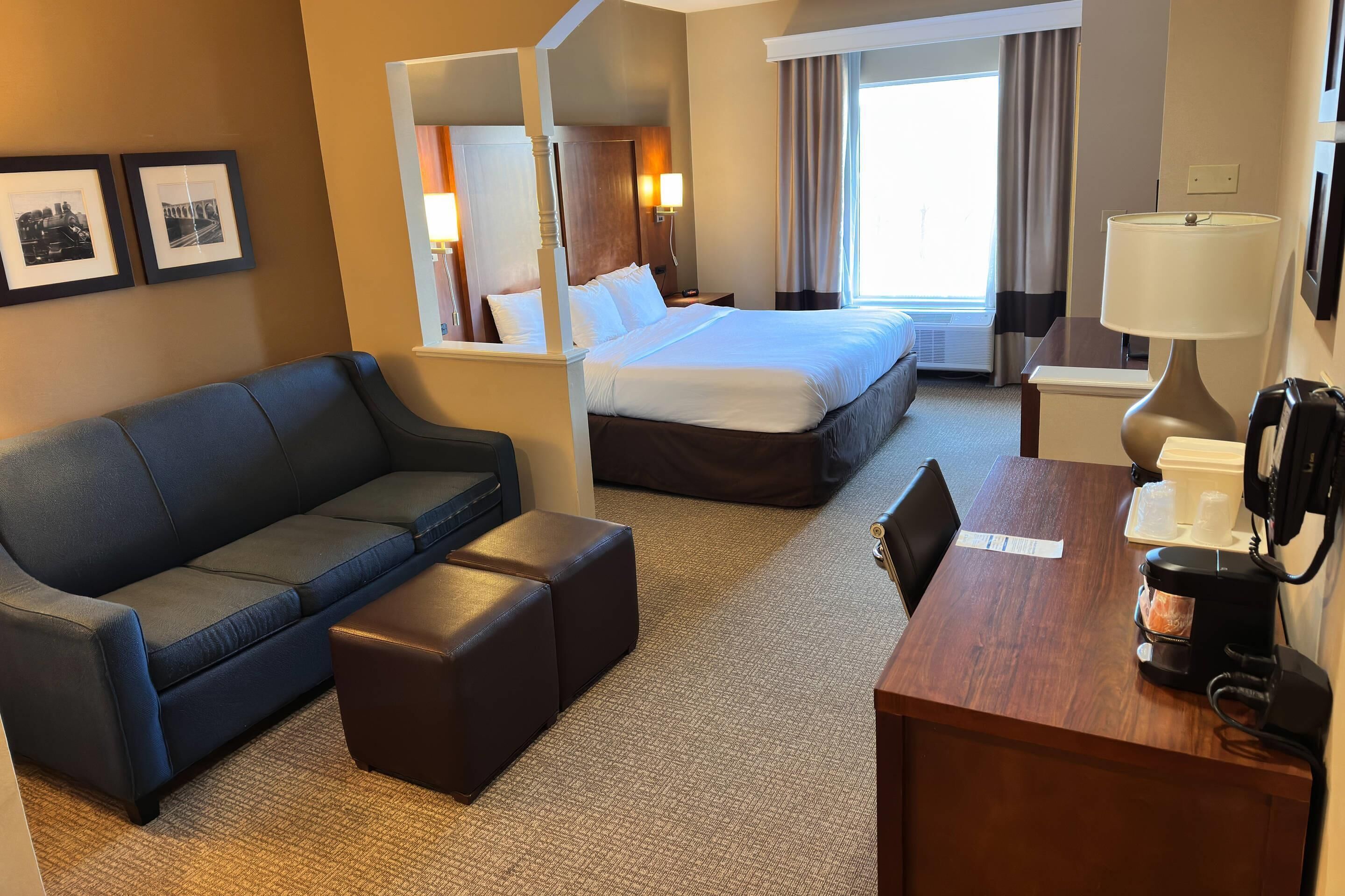 Una habitación de hotel con cama, sofá, cafetera y cuadros en la pared.