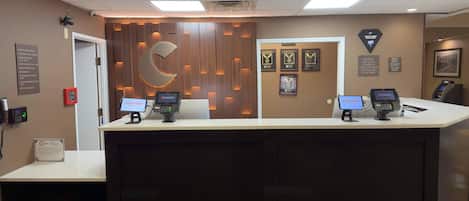 A reception desk with two computer monitors, a logo, and framed awards on the wall.